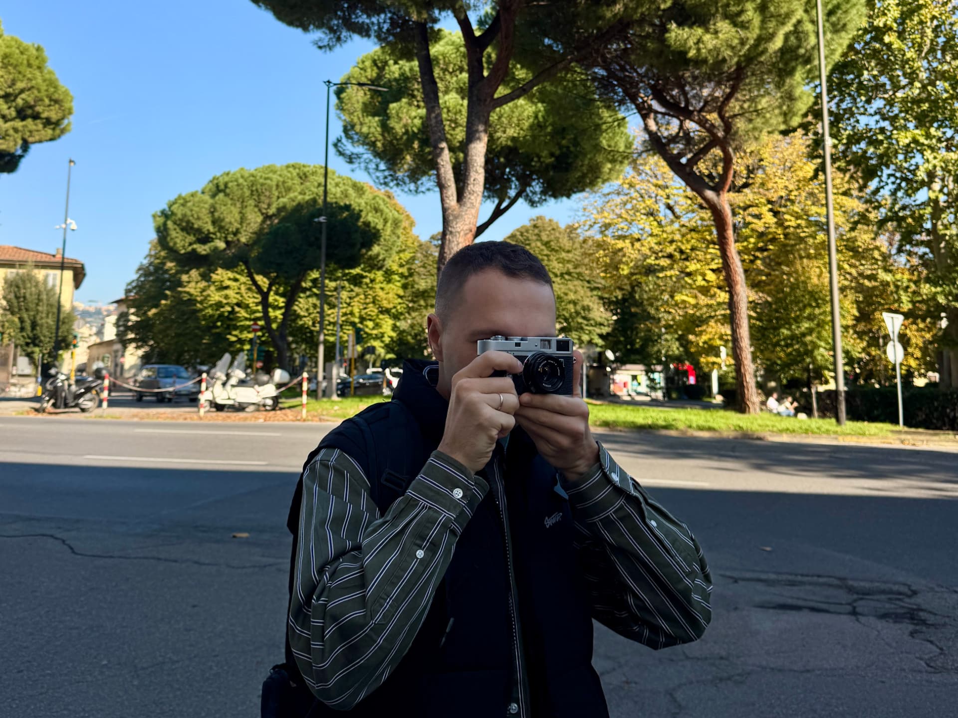 Sergei shooting a rangefinder film camera on a tree-lined street